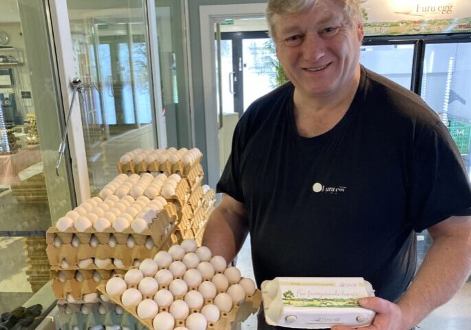 Erik fra Furu Egg smiler mens han viser frem dagsferske egg i gårdsbutikken